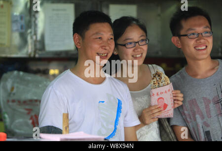 La torta a base di carne hawker Shao Jianhua, sinistra, che somiglia il presidente cinese Xi Jinping, pone per le foto con i clienti presso il suo cibo stallo nella città di Changsha Foto Stock