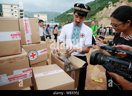 Cinese imprenditore Uighur Adil Memettur, a sinistra mostra il dado dolci (Qiegao) ha donato ai giornalisti mentre la loro distribuzione per gli abitanti dei villaggi locali interessati b Foto Stock