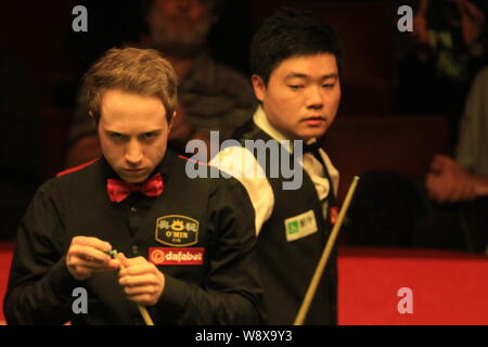 Michael Wasley dell Inghilterra, anteriore, gessi spunto come egli ritiene che un colpo contro Ding Junhui della Cina, indietro durante il primo round del Dafabet Giornate mondiali Foto Stock