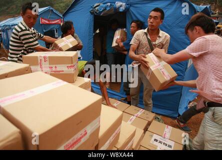 I volontari passano sui cartoni del dado dolci (Qiegao) donati dai cinesi Uighur imprenditore Adil Memettur per gli abitanti dei villaggi locali colpite dal 6,5-grandezza Foto Stock