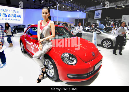 --FILE -- un modello pone con un nuovo Beetle come visitatori visualizza le altre vetture Volkswagen in un auto show di Qingdao City East Chinas provincia di Shandong, 16 maggio Foto Stock