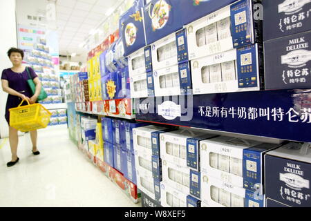 --FILE--un cliente cinese passato passeggiate cartoni di latte Mengniu Deluxe a un supermercato a Shanghai in Cina, 2 settembre 2014. China Mengniu Dairy Co's Foto Stock