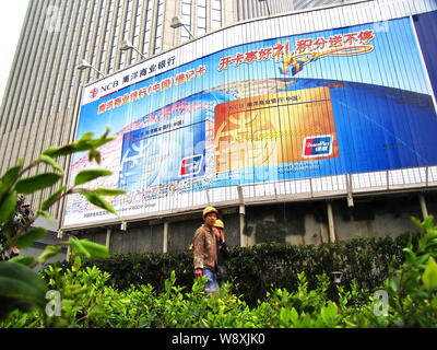 --FILE--cinese lavoratori migranti a piedi passato un annuncio per le carte di debito di Nanyang banca commerciale supportato da Cina UnionPay in Cina a Shanghai, Foto Stock