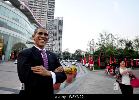 Una passeggiate a piedi passato una gomma figura di U.S. Il presidente Barack Obama sul display al di fuori del centro di vendita di immobili residenziali in progetto Luoyan Foto Stock