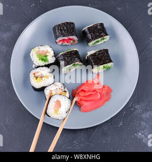 Rotolo di Sushi con bacchette grande su una piastra di sfondo rotoli con vista superiore Foto Stock