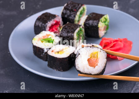 Rotolo di Sushi con bacchette grande su una piastra di sfondo rotoli con vista superiore Foto Stock