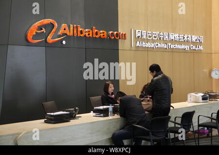 --FILE--dipendenti cinesi servono visitatori presso il banco del ricevimento in sede di Alibaba (Cina) Technology Co., Ltd. in Hangzhou, est mento Foto Stock