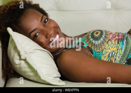 African American donna lettura sul divano di casa in soggiorno Foto Stock