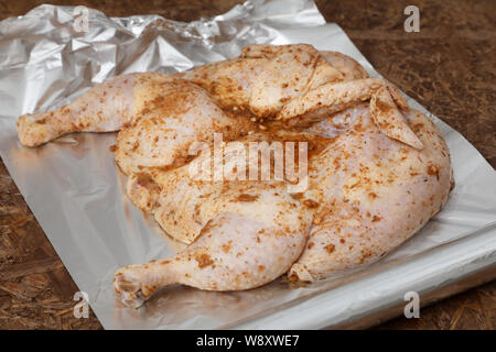 Tutto il pollo crudo è coperto con la marinata e condimento sulla lamina prima della cottura .close up Foto Stock