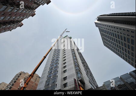 Un 260-ton heavy-duty gru viene utilizzata per demolire un illegalmente-costruzione sul tetto di un alto edificio di uffici a Pechino in Cina, 24 giu Foto Stock