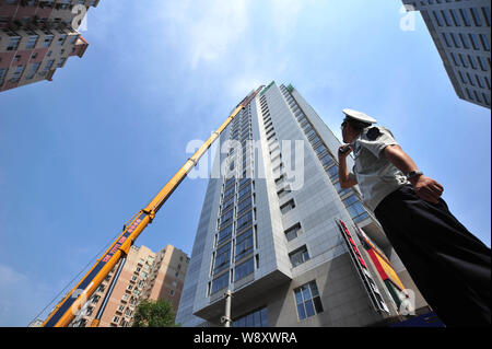 Un 260-ton heavy-duty gru viene utilizzata per demolire un illegalmente-costruzione sul tetto di un alto edificio di uffici a Pechino in Cina, 24 giu Foto Stock