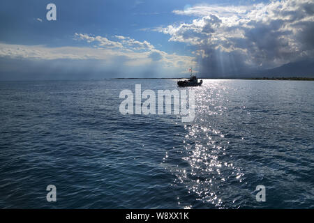 Una piccola nave all'orizzonte. Nuvole e raggi di sole sul mare. L'estate giorno nuvoloso sul lago . Issyk-kyl . Kirghizistan Foto Stock