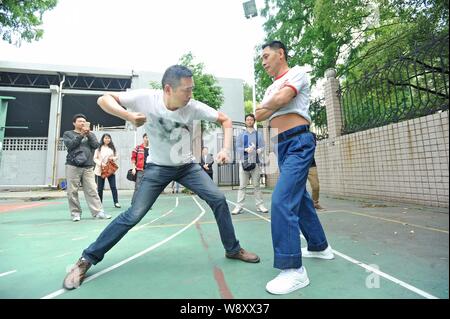 Un giovane uomo è al punzone Xie Shuiping, destra, chi fa una vita offrendo se stesso come un sacco da boxe, in un campo di pallacanestro a Wuhan City Central Ch Foto Stock