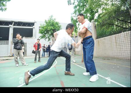 Un giovane uomo di punzoni Xie Shuiping, destra, chi fa una vita offrendo se stesso come un sacco da boxe, in un campo di pallacanestro a Wuhan City, porcellane centrale Foto Stock