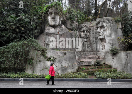 Una donna cinese passeggiate oltre le sculture in pietra di U.S. Presidenti dalla replica di porcellane del monte Rushmore National Memorial ricoperti di vegetazione di un Foto Stock