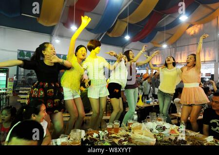 Giovani donne danza per allietare come essi godono di birra e di altri prodotti alimentari durante il ventiquattresimo Qingdao International Beer Festival in Qingdao City East Chinas Shandong Foto Stock