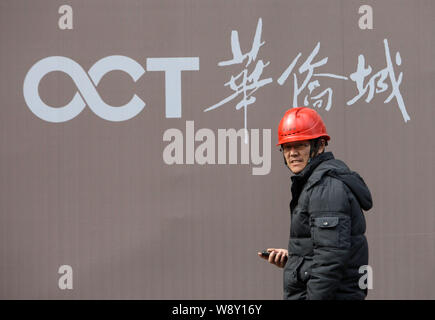 --FILE--un lavoratore cinese passeggiate passato un cartello dei PTOM (Overseas Chinese Town) in corrispondenza di un sito in costruzione in Cina a Shanghai, 17 dicembre 2012. Shanghai Foto Stock