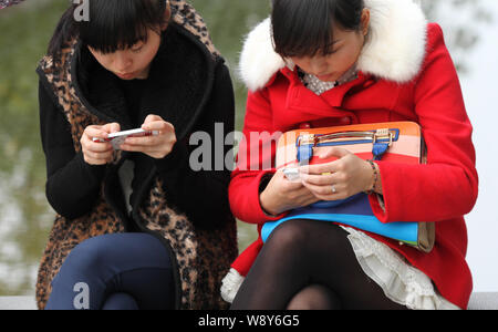 --FILE-Young le donne cinesi utilizzano il loro smartphone per navigare in Internet a un parco nella città di Nantong, est Chinas provincia dello Jiangsu, 23 novembre 2013. Ch Foto Stock