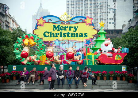 Le donne anziane resto davanti a tema natalizio di installazioni in Macau, Cina, 11 dicembre 2014. Natale sta arrivando e tutta la Cina sta diventando Foto Stock