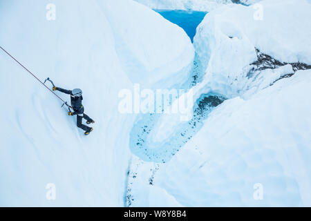 Cordata arrampicata su ghiaccio verticale su un profondo blu piscina sul ghiacciaio Matanuska in Alaska. Foto Stock