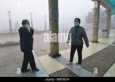 Cinesi locali residenti indossano maschere viso fare esercizi del mattino in pesanti smog in città Fuyang, est Chinas provincia di Anhui, 26 marzo 2014. Lo smog contin Foto Stock