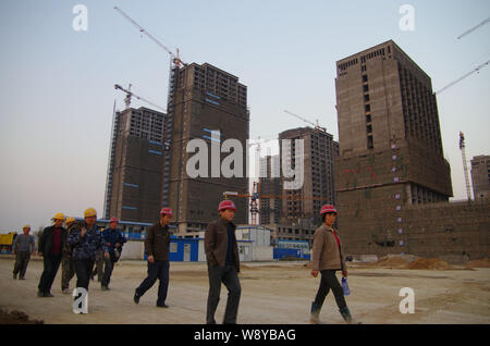 --FILE--cinese lavoratori migranti a piedi passato nuovo alto appartamento residenziale di edifici in fase di costruzione nella città di Rizhao, est Chinas Shandong provin Foto Stock