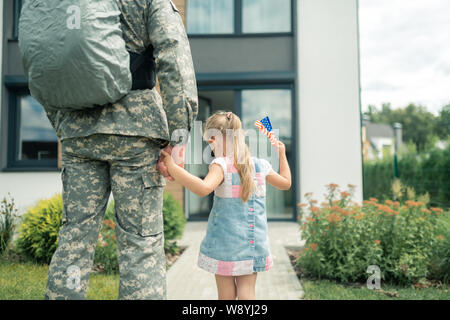 Ragazza carina tenendo la mano di suo padre che prestano servizio nelle forze armate Foto Stock