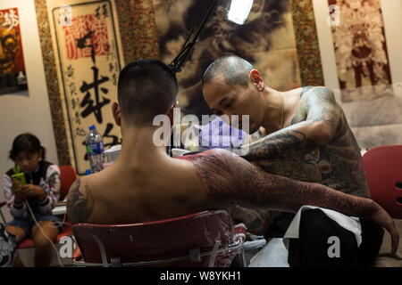 Un tatuaggio artista da Taiwan a base di potenza ad Aghi Tattoo inchiostri  il braccio di un cliente durante la Seconda Internazionale di Hong Kong  Tattoo Convention di Ko Foto stock 