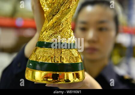 Un Cinese funzionario doganale controlla un grippaggio fake World Cup Trofeo presso un magazzino in Yiwu City East Chinas nella provincia di Zhejiang, 16 aprile 2014. Più di Foto Stock