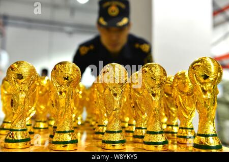 Un Cinese funzionario doganale verifica sequestrati fake World Cup trofei in corrispondenza di un magazzino in Yiwu City East Chinas nella provincia di Zhejiang, 24 aprile 2014. 18,860 fa Foto Stock