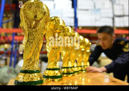 Un Cinese funzionario doganale verifica sequestrati fake World Cup trofei in corrispondenza di un magazzino in Yiwu City East Chinas nella provincia di Zhejiang, 16 aprile 2014. Più di Foto Stock