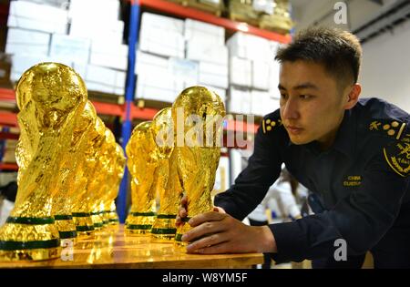Un Cinese funzionario doganale verifica sequestrati fake World Cup trofei in corrispondenza di un magazzino in Yiwu City East Chinas nella provincia di Zhejiang, 16 aprile 2014. Più di Foto Stock