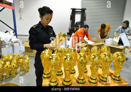 Un Cinese funzionario doganale verifica sequestrati fake World Cup trofei in corrispondenza di un magazzino in Yiwu City East Chinas nella provincia di Zhejiang, 16 aprile 2014. Più di Foto Stock