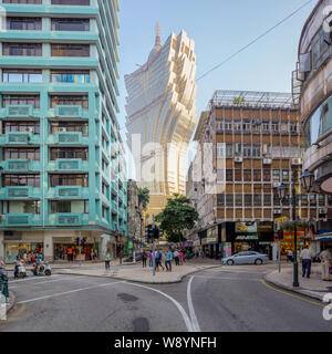 --FILE--i pedoni e i ciclisti passare da vecchi edifici e il Grand Lisboa Casinò, Centro, Macau, Cina, 20 ottobre 2013. Il portoghese ex Foto Stock