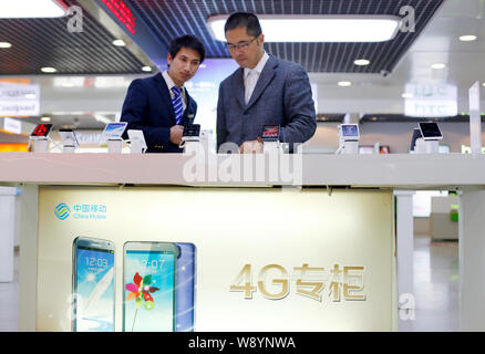 --FILE--un cliente cinese tenta di eseguire 4G smartphone supportati in corrispondenza di un ramo di China Mobile in Hangzhou, est Chinas nella provincia di Zhejiang, 2 Dicembre Foto Stock