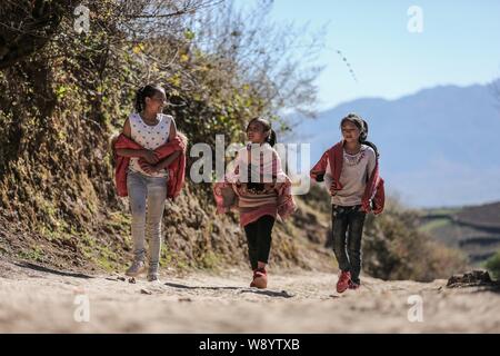 Le giovani ragazze a piedi lungo una strada di montagna in un villaggio di poveri in Daliang Montagna in Liangshan Yi prefettura autonoma, a sud-ovest della Cina di provincia di Sichuan Foto Stock