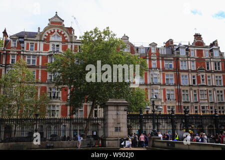 La facciata di un edificio di mattoni rossi di fronte al British Museum e persone di lasciare il museo al cancello principale in Bloomsbury, Londra, Regno Unito. Foto Stock