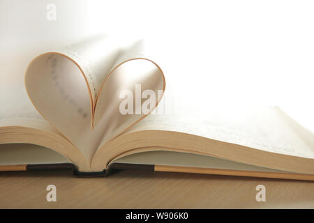 Due pagine in un libro aperto che crea una forma a cuore Foto Stock