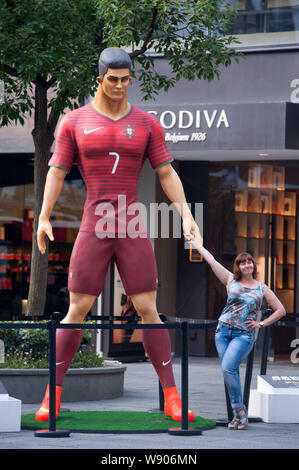 Un visitatore pone con una figura gigantesca di calcio portoghese superstar Cristiano Ronaldo sul display a Xintiandi, una attrazione turistica complesso nel fare Foto Stock