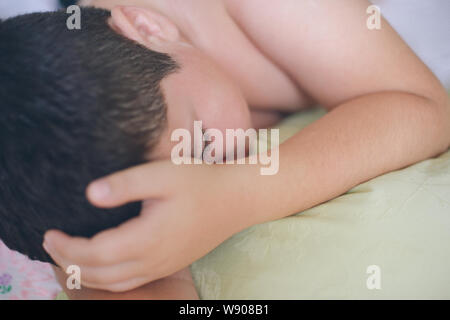 Dormendo poco caucasian boy con gli occhi chiusi giacente sul cuscino verde durante il sonno profondo in mattinata Foto Stock