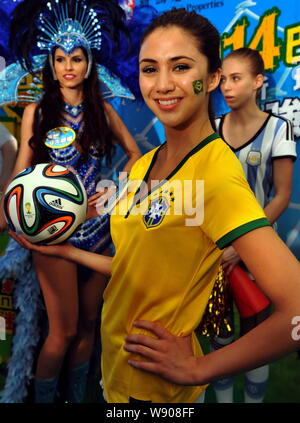 Una showgirl vestito con una maglietta di calcio del Brasile national team pone con un 2014 FIFA World Cup Brasile Pallone da calcio durante un evento da celebrare la up Foto Stock