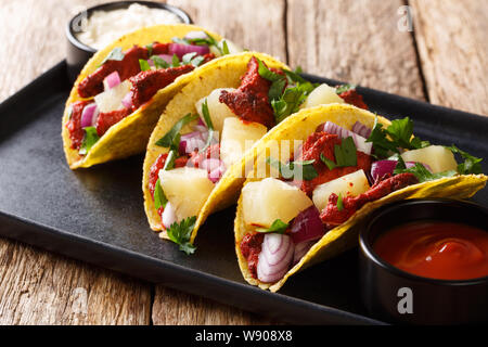 Tacos messicano al pastore servito con salsa di primo piano su una piastra sul tavolo orizzontale. Foto Stock