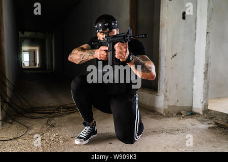 Un personaggio di un gioco Airsoft è raffigurato, tenendo una pistola M15, indossando una bandana sulla testa e mostrando un tatuaggio Foto Stock