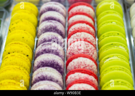 Sfondo sfocato vetrina pasticceria. Righe liscia di biscotti torte, giallo rosso porpora macarons bianco sul bancone di un negozio di caramelle, Caff, s Foto Stock