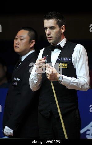 Mark Selby di Inghilterra, diritto, gessi spunto come egli ritiene che un colpo contro Fergal O'Brien dell Irlanda durante la loro quarterfinal match di 2014 Giornate mondiali Foto Stock