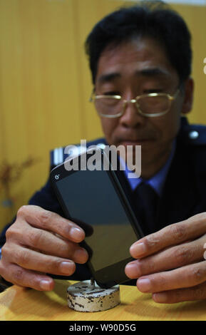 Cui Juguo, che ha stabilito un nuovo record mondiale per il bilanciamento di un uovo di struzzo su un perno, si prepara a bilanciare un smartphone su un punto dell'ago nella città di Changsha, Foto Stock