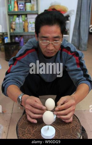 --FILE--cui Juguo, che ha stabilito un nuovo record mondiale per il bilanciamento di un uovo di struzzo su un perno, saldi due uova su punti di ago nella sua casa di Changsha c Foto Stock