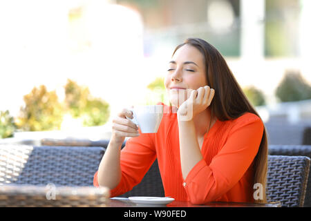 Donna rilassate gustando la prima colazione annusare il caffè seduti in un bar terrazza Foto Stock