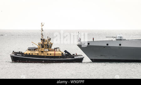 Un rimorchiatore che assiste il SAS Amatola dalla Simons Town base navale sul Sud Africa False Bay costa vicino a Città del Capo Foto Stock