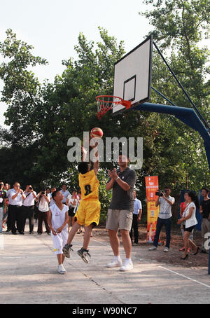 Pensionato cinese superstar di basket Yao Ming, più alti, applaude come Egli veglia dei giovani studenti giocare a basket in una scuola primaria per promuovere Yao Fo Foto Stock